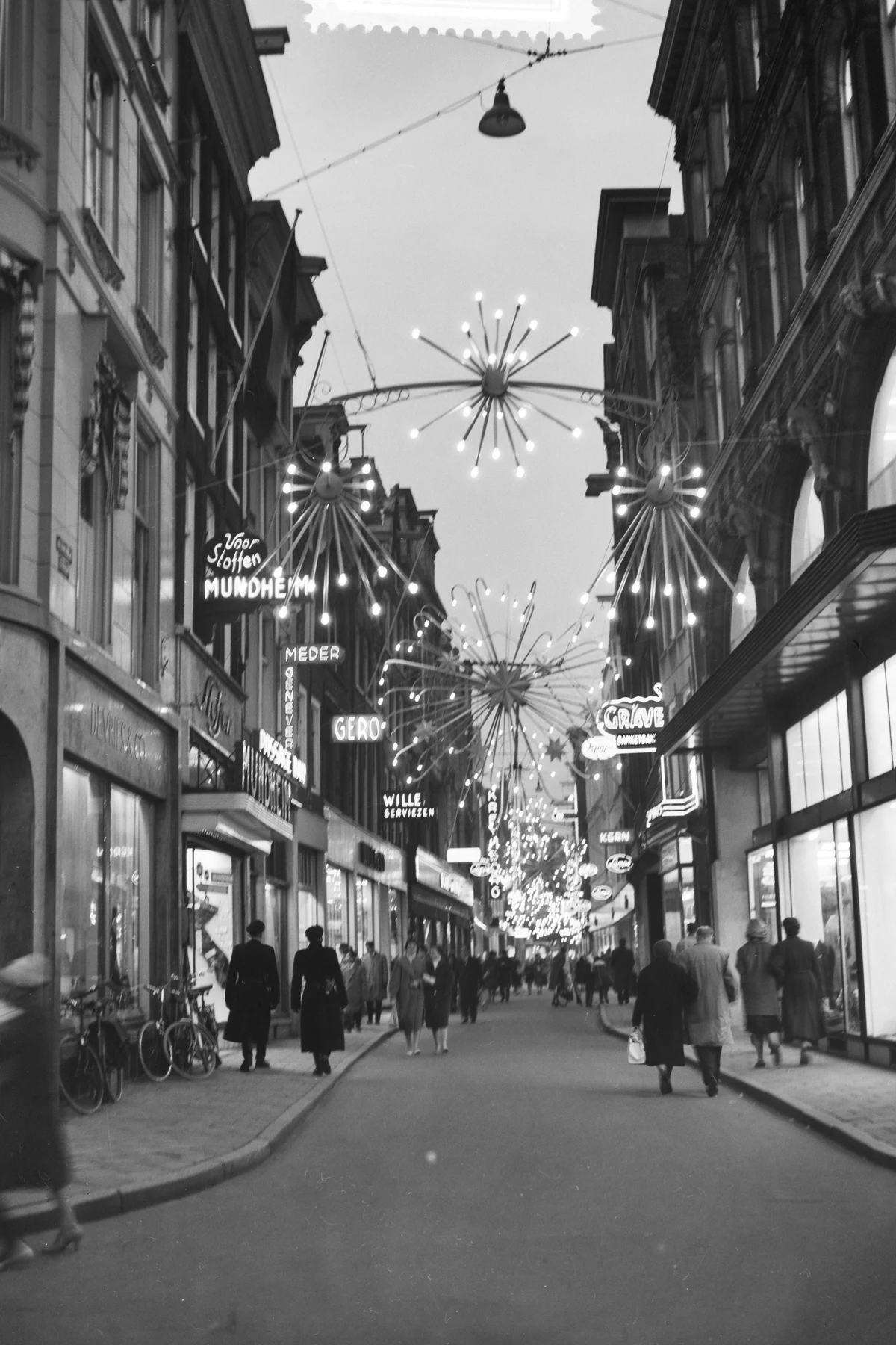 灯饰悬挂在历史街道上方并延伸至远处的黑白城市夜景