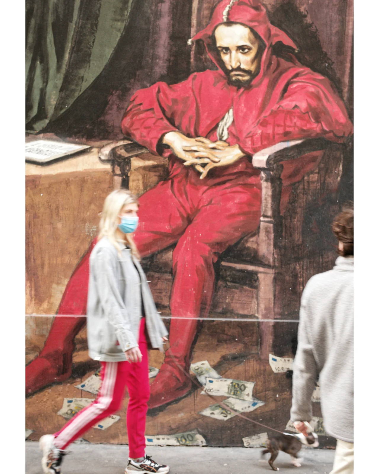 行人经过红色人物主题墙绘的街道画面